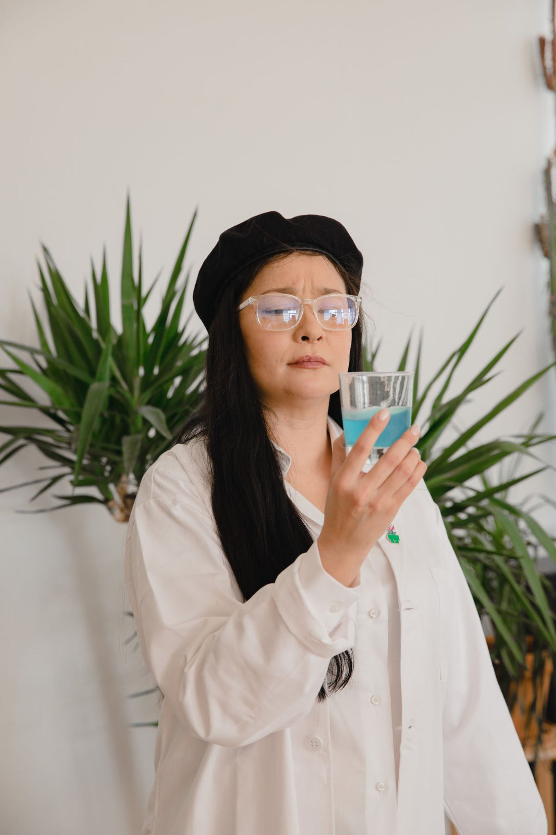 Glass of blue mouthwash held in hand