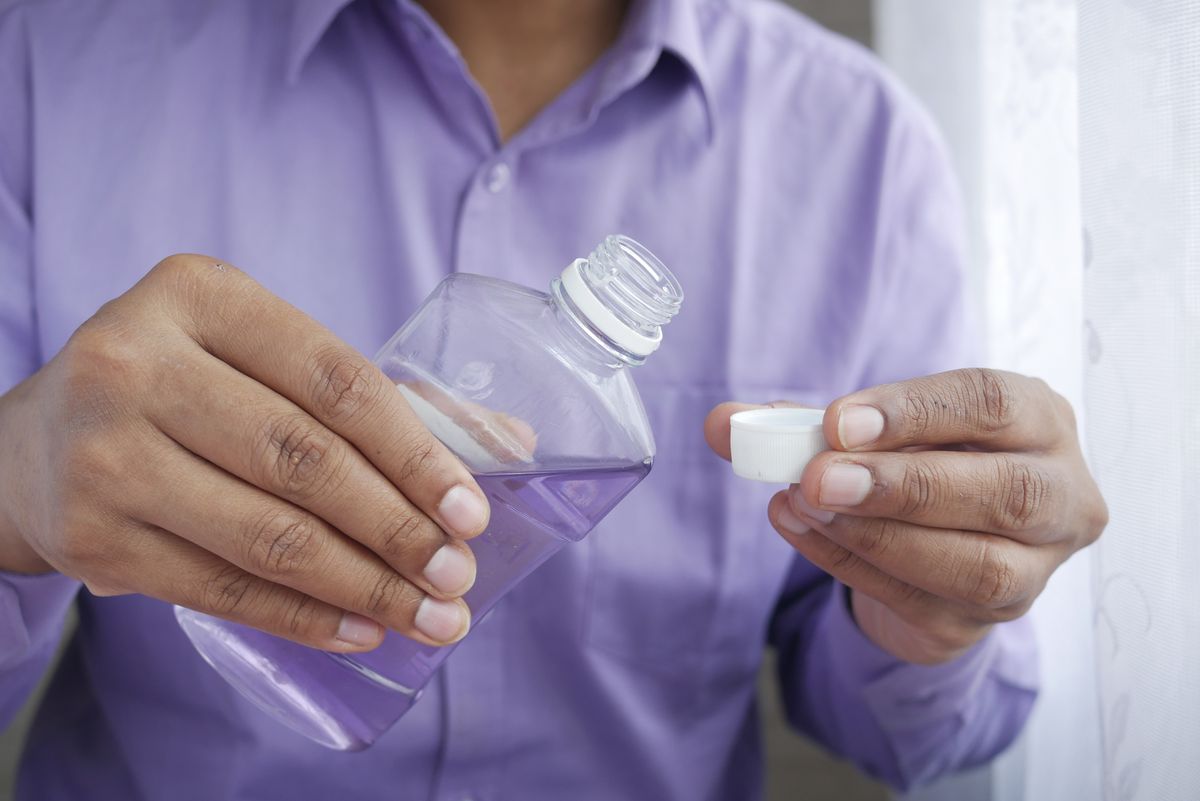 Pouring mouthwash into a measuring cap